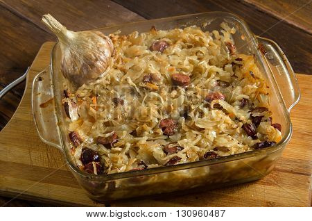 Baked sauerkraut with sausages on wooded table