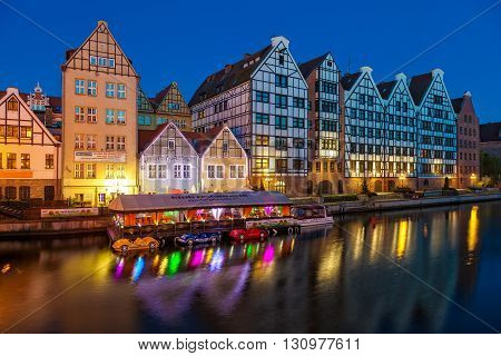 GDANSK, POLAND - MAY 05, 2016: Old historic granaries on the Granary Island with a restaurant on the water at night. Old Town in Gdansk is a tourist attraction for visitors.