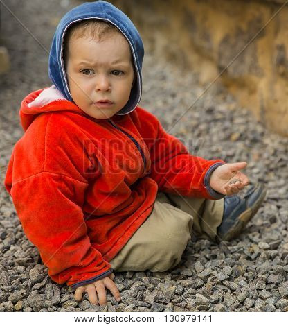 brooding boy playing his toy in the backyardsitting on the gravel