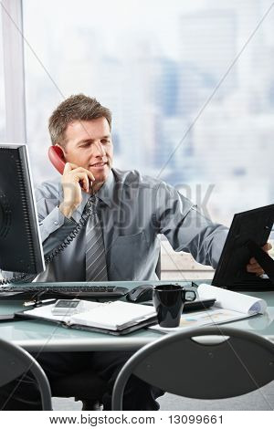 Gelukkig zakenman met gesprek op vaste telefoon kijken naar familie foto glimlachen.