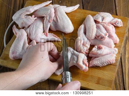 a man cut the chicken wings on a wooden table