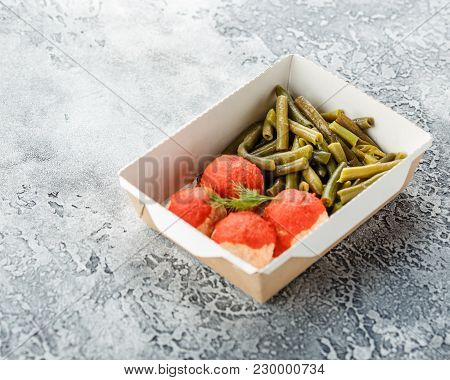 Boiled String Beans And Fish Balls In Sauce In A Lunchbox On A Gray Background. Healthy Food Deliver