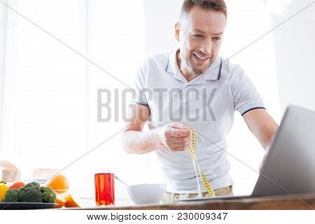Diet Result. Cheerful Attentive Man Transferring Data In Program For Biohacking While Holding Metre 