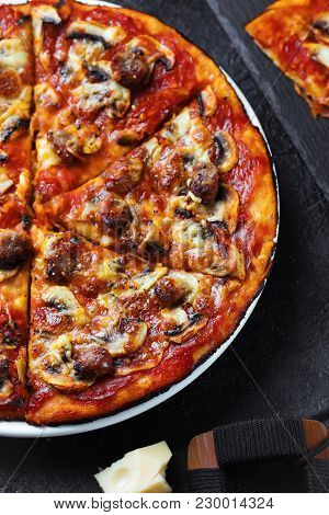Homemade Pizza With Chorizo, Mushrooms, Mozzarella And Pieces Of Chipolata Sausages On Dark Table. T