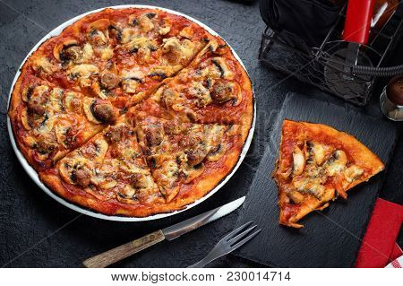Homemade Pizza With Chorizo, Mushrooms, Mozzarella And Pieces Of Chipolata Sausages On Dark Table. T