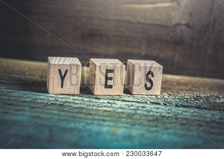 Macro Of The Word Yes Formed By Wooden Blocks On A Wooden Floor