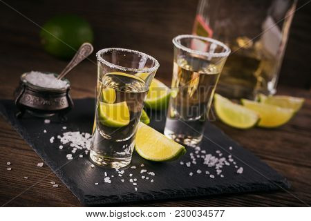 Gold Tequila Shot With Lime And Sea Salt On Black Table.