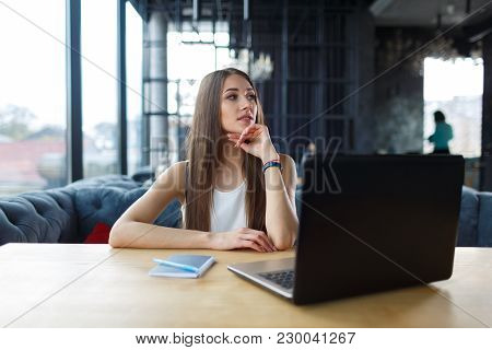 Young Woman Working On Her Laptop In The Restaurant. Student Waiting For Her Order .