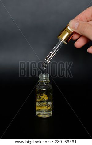 Gold Glittering Serum Bottle With Dropper In Woman Hand. Centered Possition