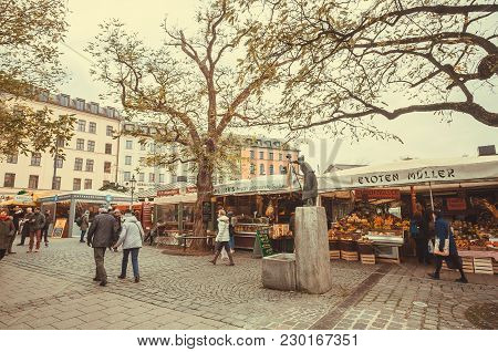 Munich, Germany - November 16, 2017: People Walking In Historical City With Old Small Stores And Mar