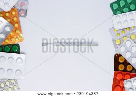 Photometer Of A Thermometer On A White Background Among Tablets Of Different Colors In Packages Of 2