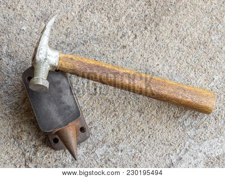 Old Small Hammer And Miniature Anvil With Concrete Background