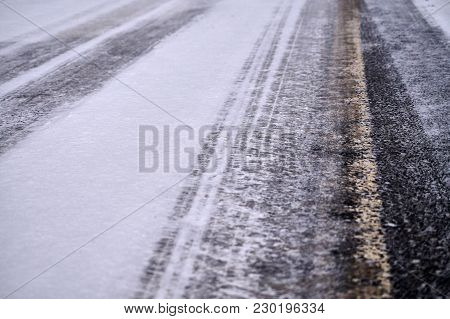 Tracks In Snow On Winter Asphalt Road.