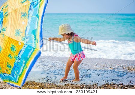 Child On The Beach Under An Umbrella
