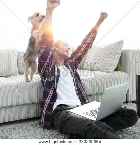 happy guy exults with his dog sitting near the sofa in the livin