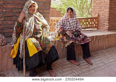Abyaneh, Iran - April 26, 2017: Two Elderly Iranian Women Are Sitting And Smiling In A Traditional V