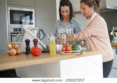Friends cooking together with kitchen robot and tablet