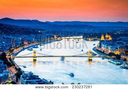 Budapest, Hungary. Dramatic Sunset Over Szechenyi Chain Bridge And The Parliament, Danube River.