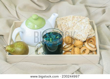 Breakfast In Bed In A Wooden Tray With Pear, Bisquits, Sweet Cookies, Teapot And Cup Of Organic Blue