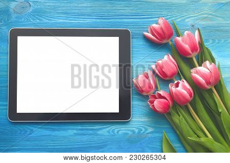 Tulip Flowers And Tablet Computer Device With Blank Screen On Blue Wooden Table Board Background Wit