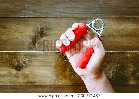 Man Hands Squeezing Hand Grips On Wooden Background