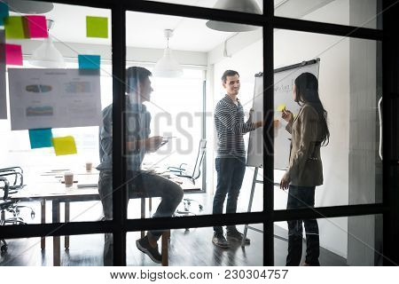 Group Of Young Business People Discussing About Their Business Plan At Modern Startup Office. Meetin