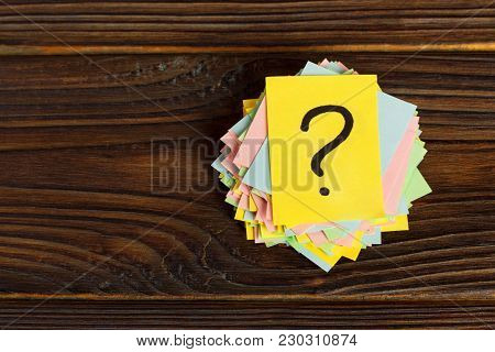 Question Mark Paper Heap On Wooden Table Concept For Confusion.
