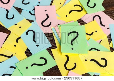 Pile Of Colorful Paper Notes With Question Marks On Wooden Background. Closeup.