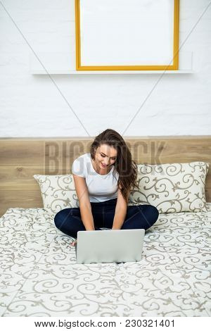 Woman In Bed With Laptop On Legs At Home