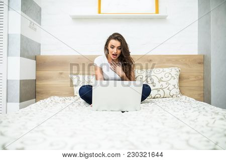 Woman In Bed With Laptop On Legs At Home