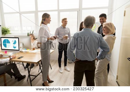 Smiling Happy Young And Senior Multi-ethnic Workers Talking In Coworking, Diverse Corporate Staff Ha