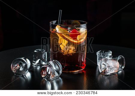 Alcoholic Cocktail In A Glass Of Ice. The Ice On The Table And On Black Background