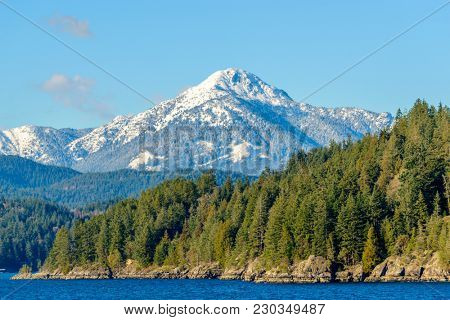 Fantastic view over ocean, snow mountain and rocks at Sechelt inlet in Vancouver, Canada.
