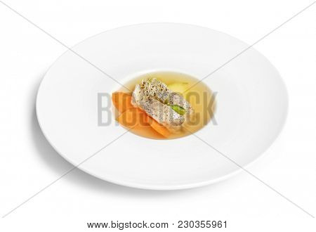 Delicious consomme soup with pieces of codfish in plate on white background