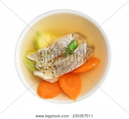 Delicious consomme soup with pieces of codfish in bowl, top view