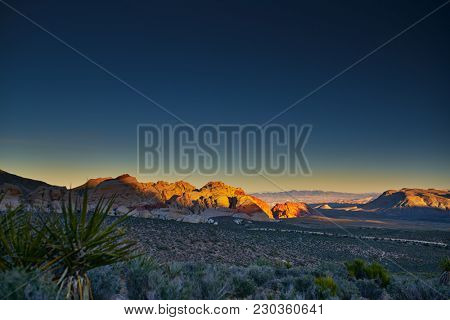 sun setting over redrock canyon rocks with las vegas in background