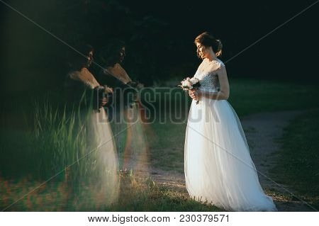 Young Woman In A White Dress Is Standing On The Field. Portrait Of Girl Outdoor. Romantic Young Woma
