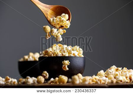 Popcorn Falls From A Wooden Spoon Into Bowls And Around Them.