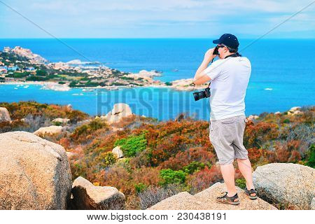 Man With Camera Taking Photos Of The Mediterranian Sea At Capo Testa, Santa Teresa Gallura, Sardinia