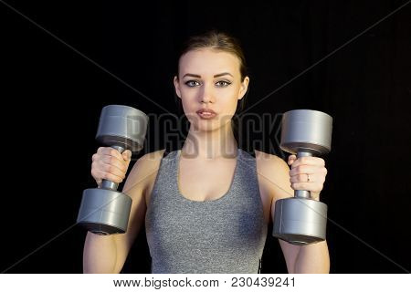 The Athlete Is Engaged With Heavy Dumbbells On A Black Background.