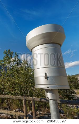 Weather Station With Metallic Rain Gauge On A Blue Sky With Clouds