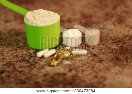 Whey Protein Powder In Scoop With Vitamins. Athletes Require Multiple Supplements To Remain Healthy.