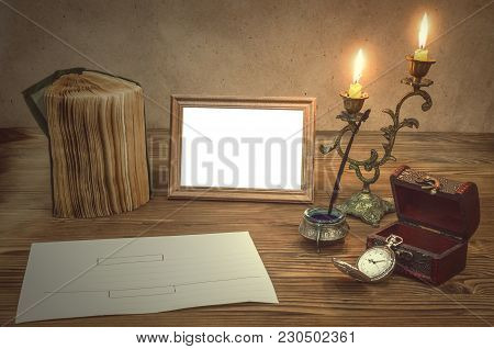 The Letter. Empty Photo Frame With Copy Space, Book And Burning Candle In Vintage Candlestick Feathe