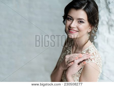 Half Length Portrait Of Brunette Smiling Woman Dressed In Sleeveless Light Evening Dress.