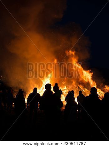 Silhouettes Of People In Frontof Big Fire