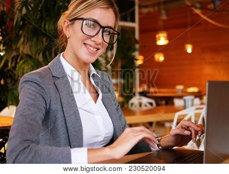 Business wooman using laptop at cafe. Young beautiful girl sitti