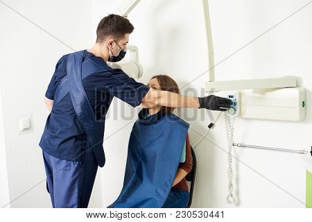 Young Professional In A Blue Uniform Is Taking Care Of A Female Patient While Making An X-ray Shot I