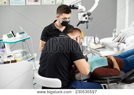 Assistant In A Black Mask And Gloves Helps The Dentist In The Process Of Treating The Patient. Moder