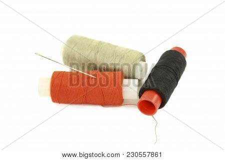Spools With Multi-colored Sewing Thread And Needle Isolated On White