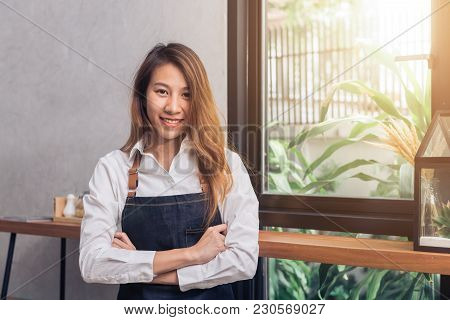 Protrait Of Young Asian Female Barista Welcome Her Customer To Coffee Shop In Warm Light Afternoon W